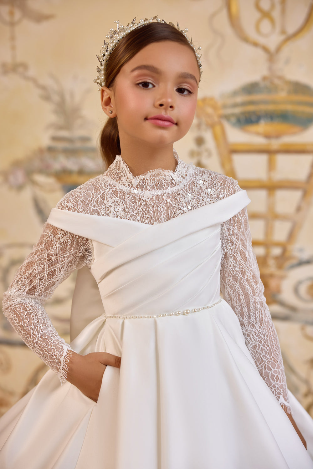 Gabriela luxury First Communion gown with illusion lace bodice, off-the-shoulder neckline, oversized bow, and cathedral-length satin train.